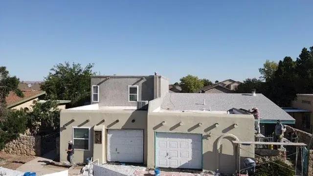Crew working on a stucco home with parapet walls and canales during an exterior finish job
