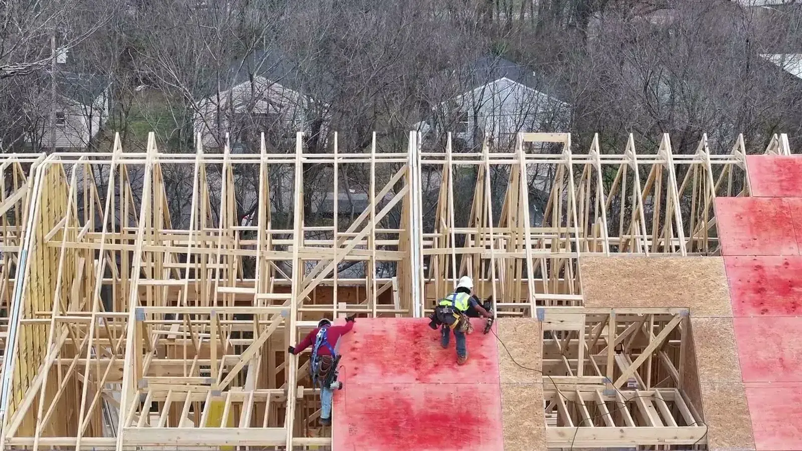 House under construction with timber framing and OSB structural sheathing panels, the same panel material used for roof decking