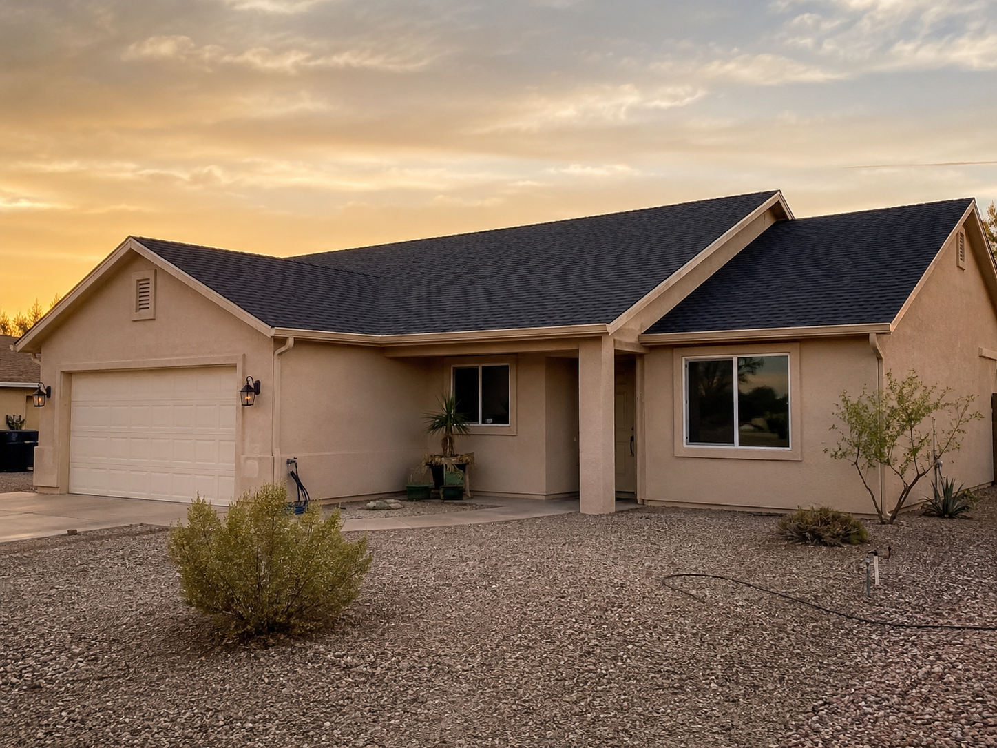 Southwest home exterior with shingle roof at dusk