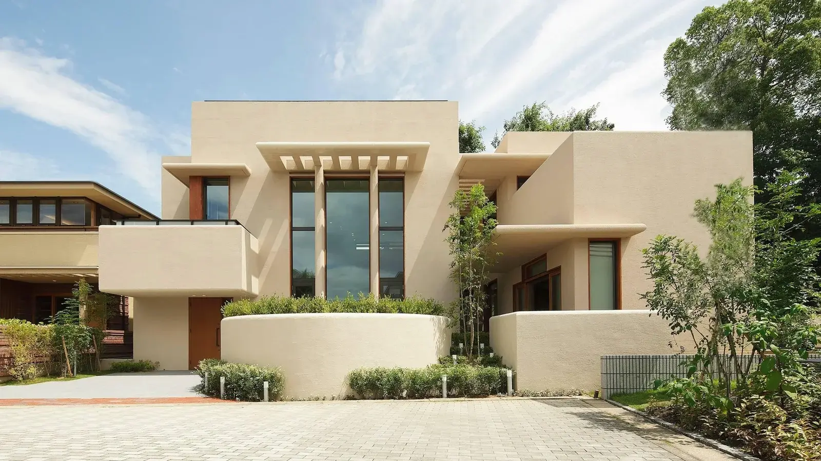 Modern flat-roofed building with a smooth, light-coloured stucco-style exterior finish and deep overhangs