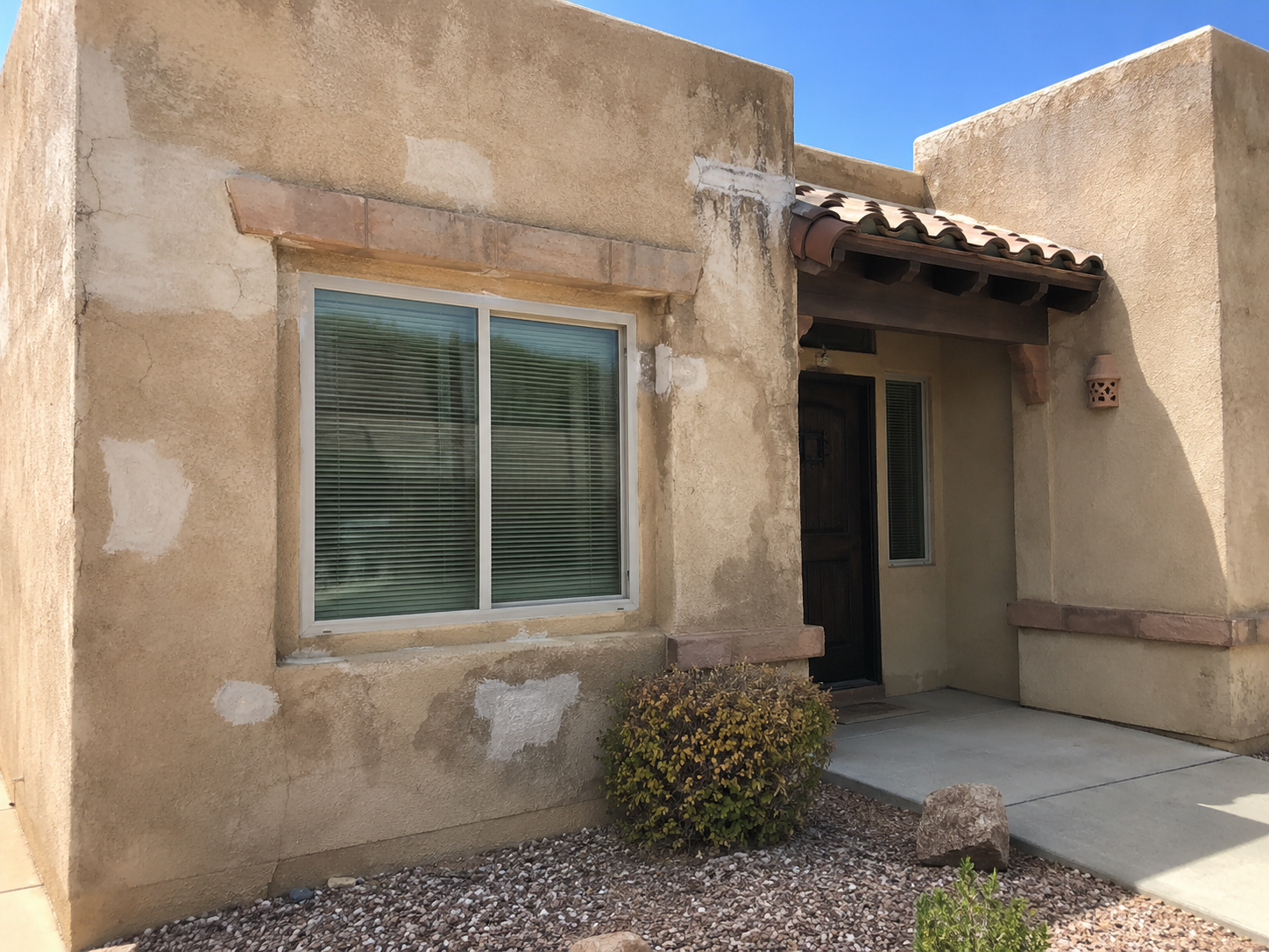 Stucco wall with patched, unfinished repair areas